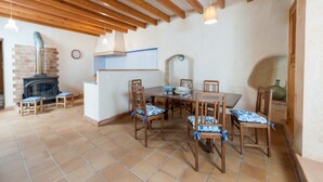 A dining area with a wooden table and chairs, a brick fireplace, and a tiled floor. - Ses Roques in Santa Maria del Cam (Santa Maria del Camí)
