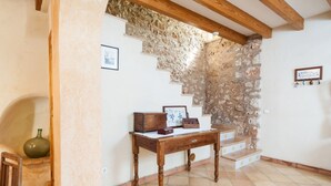 A room with a stone wall, wooden beams, a wooden table with a vase, and a framed picture. - Ses Roques in Santa Maria del Cam (Santa Maria del Camí)