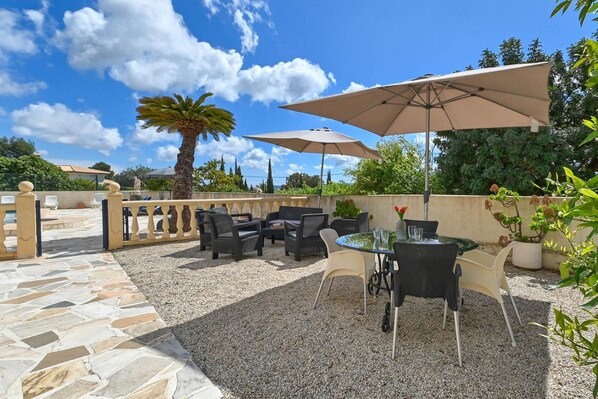 An outdoor patio area with stone flooring, wicker furniture, and umbrellas. - Ker Blanc in J vea With 5 Bedrooms and 4 Bathrooms (Javea)