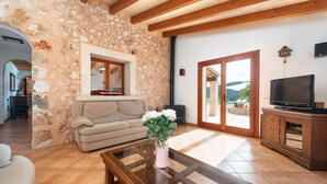 A living room with a stone wall, a sofa, a glass coffee table, and a television.