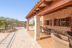 A patio area with stone flooring, outdoor furniture, and a pergola structure. - Can Lliganya in Santa y (Felanitx)