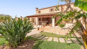 A stone house with a patio, outdoor furniture, and tropical plants.