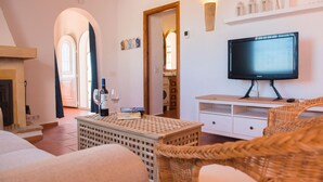 A living room with a fireplace, a television, wicker furniture, and a bookshelf. - Los Lobitos in Cumbre del Sol (Javea)