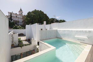 A rooftop swimming pool with a view of a historic building and lush greenery in the background. - Luxe Madre De Dios in Sanlucar de Barrameda (Sanlucar de Barrameda)