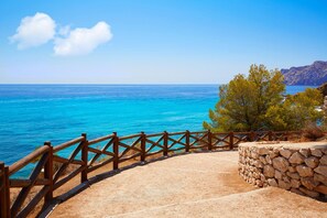 Une vue sur la côte, avec une clôture en bois, un mur de pierre et une mer bleue et limpide.