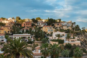 Un quartier résidentiel situé sur une colline, avec des maisons à étages, des palmiers et un ciel dégagé.