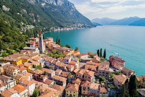 Un borgo costiero con edifici colorati, un campanile imponente e una vista limpida sul lago.