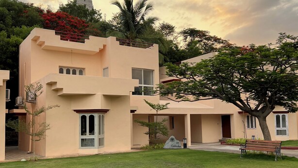 A modern building with a flat roof, multiple windows, and a well-maintained lawn. - Kyra Wellness Resort (Hyderabad)