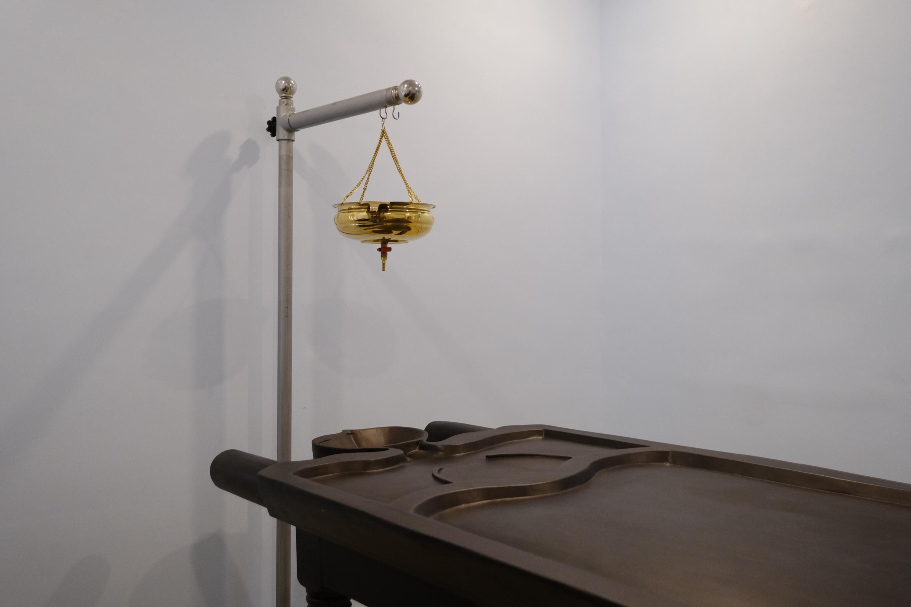A scale with a bowl on a stand, a tray with a bowl, and a wall.