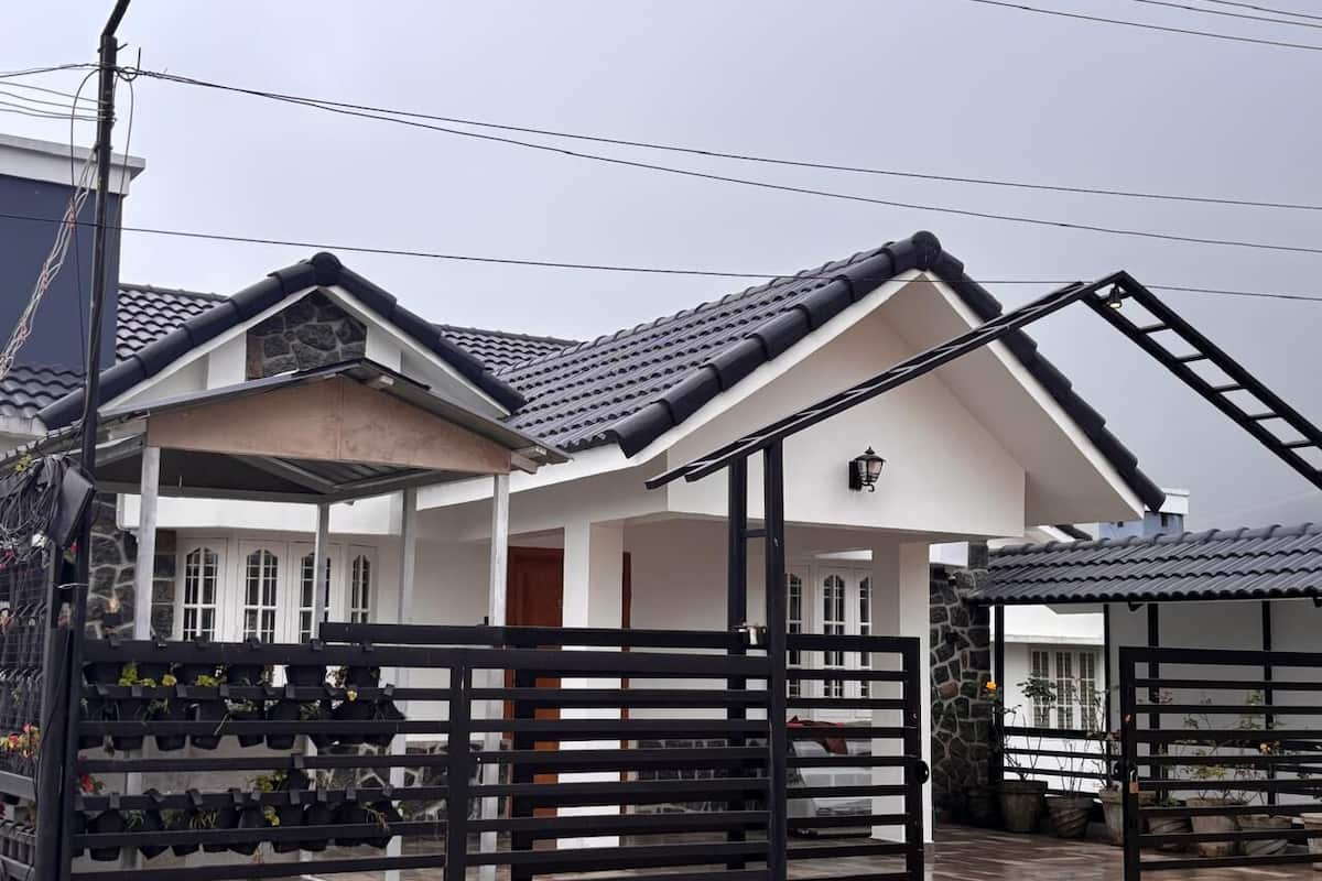 A two-story house with a stone facade, a tiled roof, and a gated entrance.