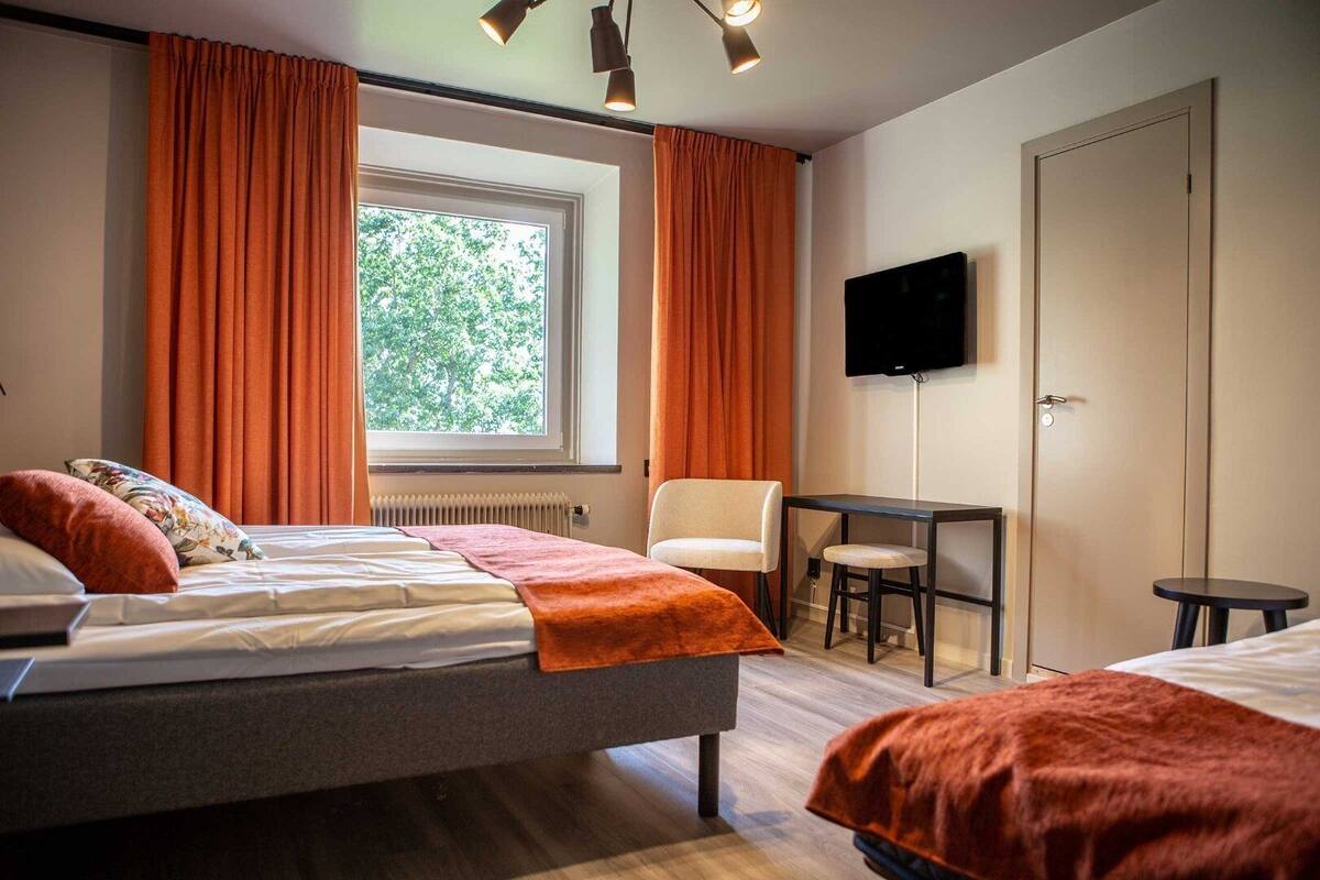 Une chambre d’hôtel avec un lit, une chaise, une petite table et un téléviseur.