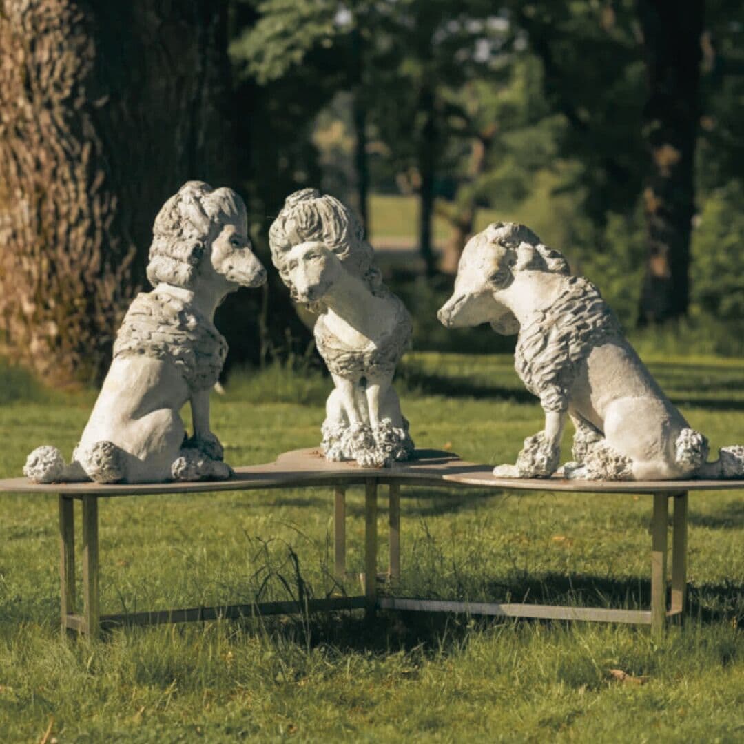 Drie stenen beeldjes van dieren op een houten tafel in een grasrijke omgeving.