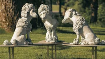 Drie stenen beeldjes van dieren op een houten tafel in een grasrijke omgeving.