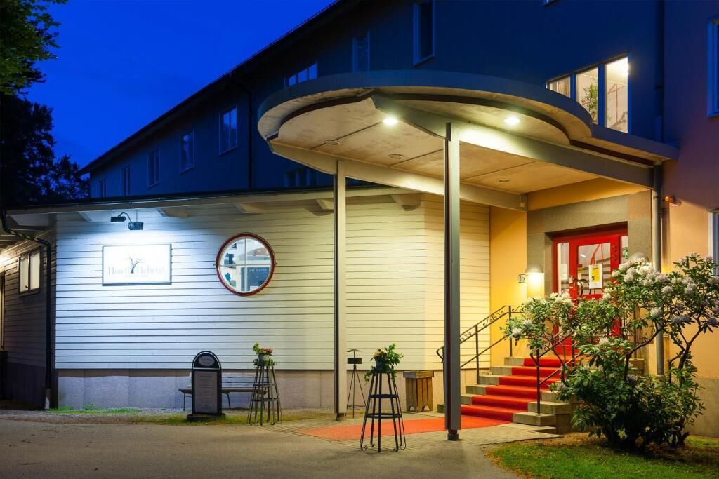 A building with a curved entrance canopy, a red door, and a staircase leading to the entrance.
