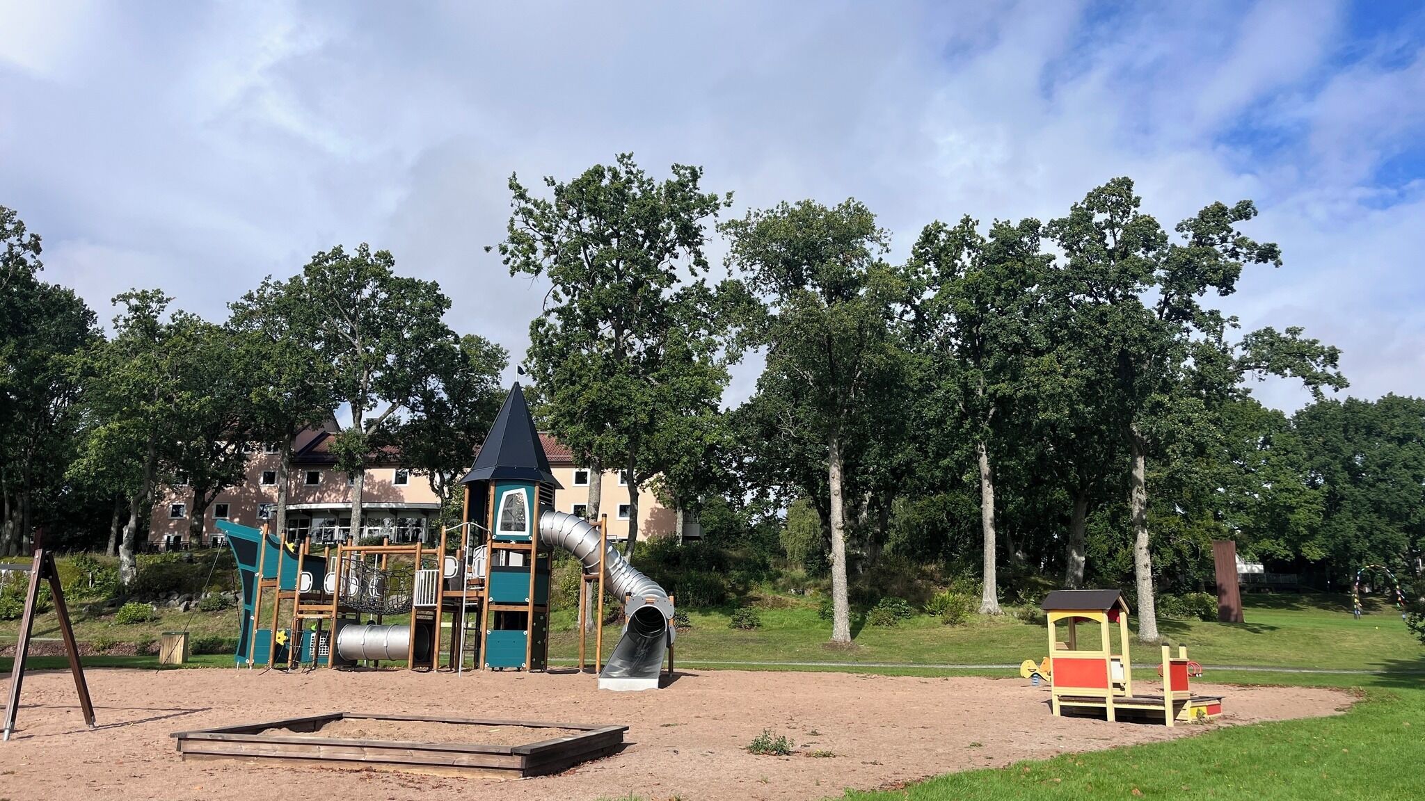 Ein Spielplatz mit Rutsche, Klettergerüsten und einem kleinen Gebäude.