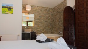 Une chambre d’hôtel avec un lit, une salle de bain avec une baignoire et une grande porte en bois.