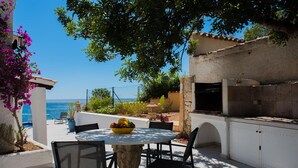 Une terrasse extérieure avec une table ronde, des chaises et un saladier rempli de fruits.