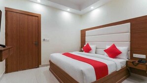 Une chambre à coucher avec un cadre de lit en bois, du linge de lit blanc et des touches de couleur rouge.