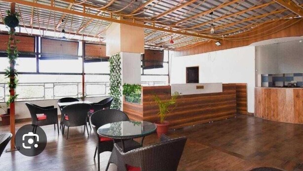 Un espace intérieur spacieux doté d’un plancher en bois, de chaises noires, d’une table en verre et d’un comptoir d’accueil.