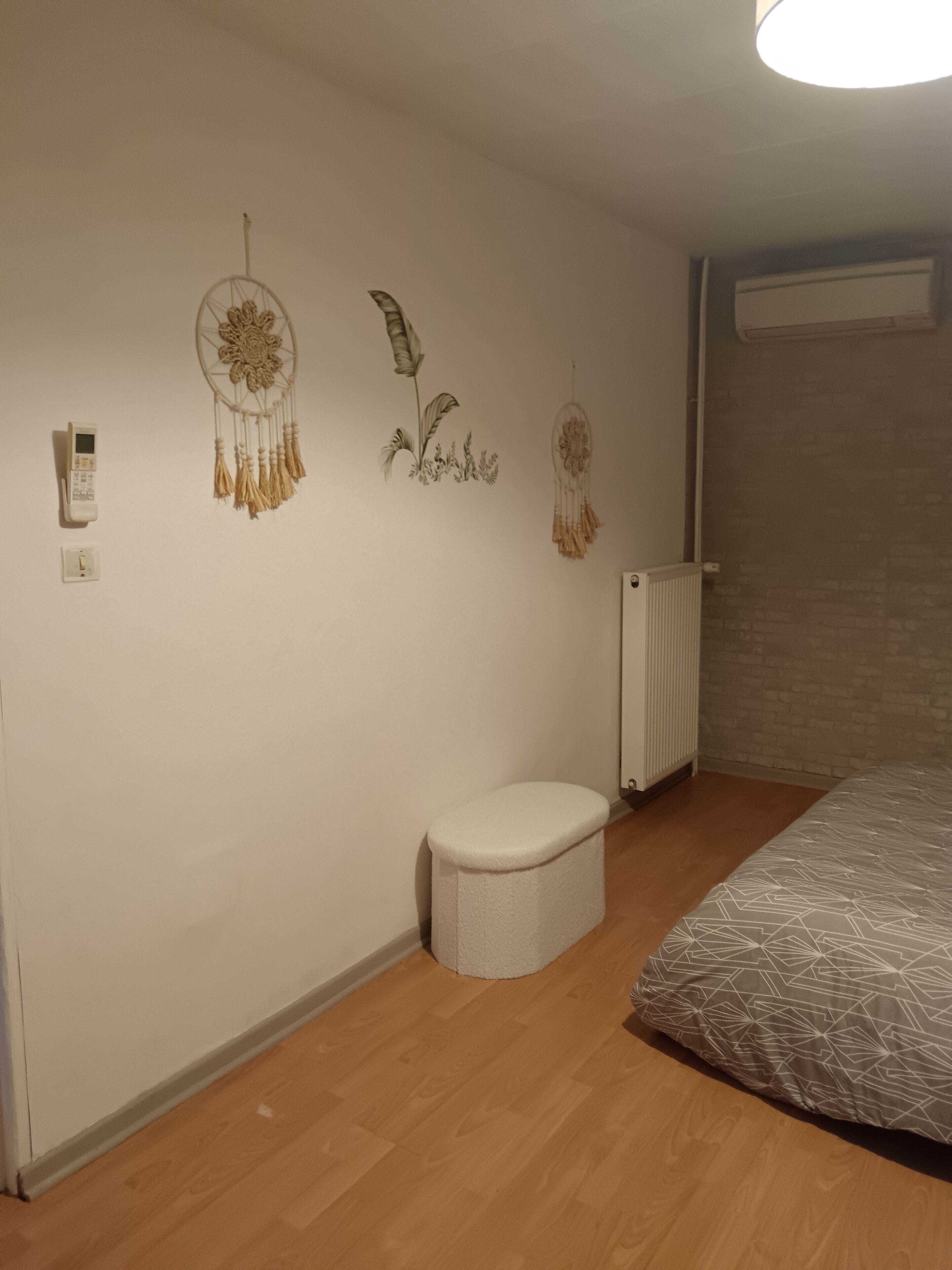 Ein Schlafzimmer mit einem Bett, einer weißen Toilette und Wanddekorationen, darunter Traumfänger.