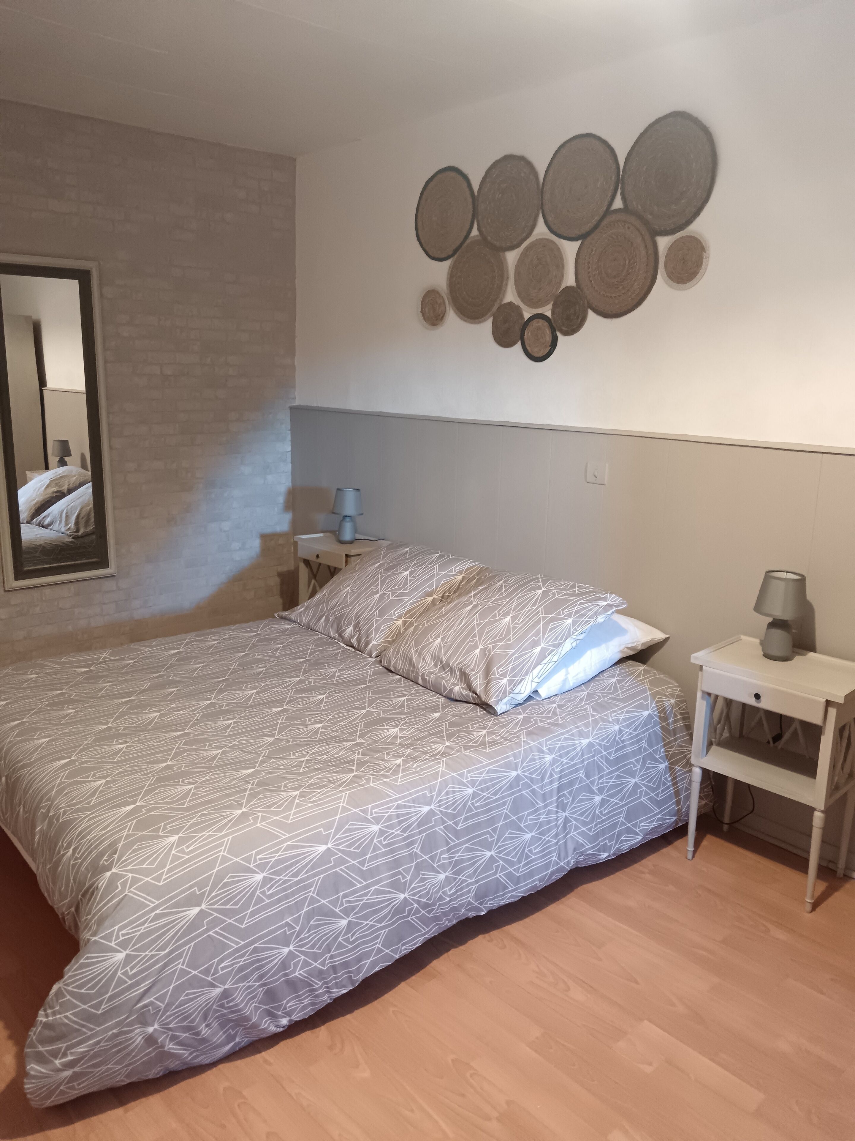 A bedroom with a bed, a nightstand, a lamp, and a wall decoration.