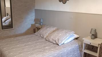 A bedroom with a bed, a nightstand, a lamp, and a wall decoration.