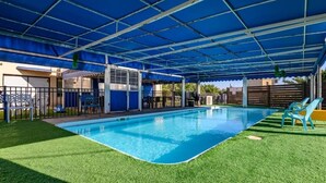 An indoor swimming pool with a blue roof and artificial grass around it. - Adi Hacarmel (Daliyat al-Karmel)
