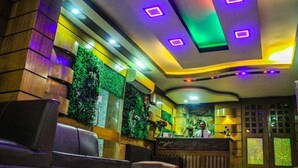 A hotel lobby with a reception desk, seating area, and a wall with greenery. - Grand Plaza Hotel (Dhaka)