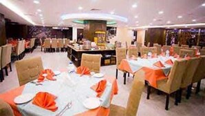 A restaurant with multiple tables set for dining, each with orange napkins and white tablecloths. - Grand Plaza Hotel (Dhaka)