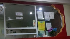 Un'area reception con una finestra in vetro, una sveglia e diversi avvisi, tra cui uno per l'hotel SV Andalal.