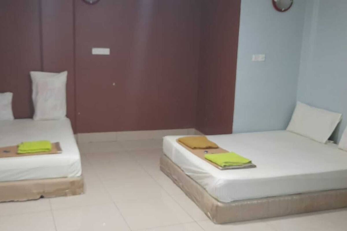 A room with two beds, each with a mattress and pillows. There are two bedside tables with items on them.