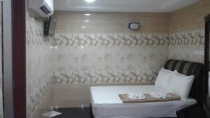 Una camera d'albergo con un letto, una TV e un condizionatore d'aria a parete.