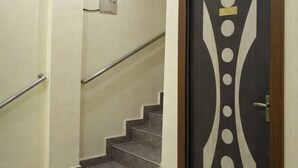 Una scala con corrimano, una ventola a soffitto e una porta con motivo geometrico.