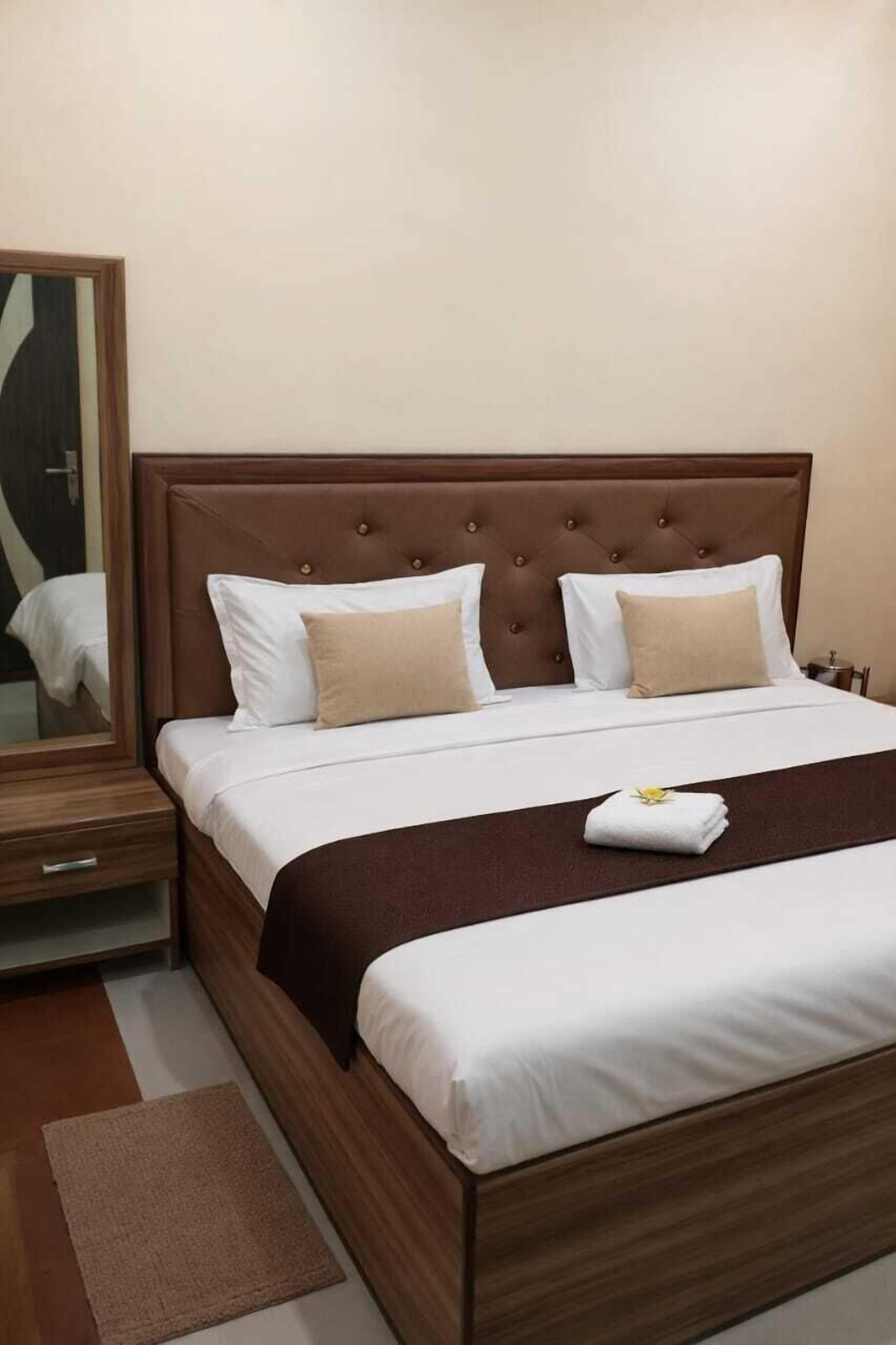 A neatly made bed with a wooden headboard, a bedside table, and a mirror.