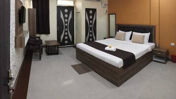A hotel room with a large bed, a desk, a chair, and a TV.