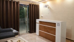 Un soggiorno moderno con un divano, un tavolino, una scrivania della reception e una porta scorrevole in vetro che dà su un balcone.