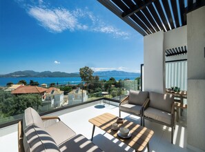 A balcony with a view of the sea and mountains, furnished with a sofa, chairs, and a table. - Fraxi Beach Premium Apartments (Nikiana)