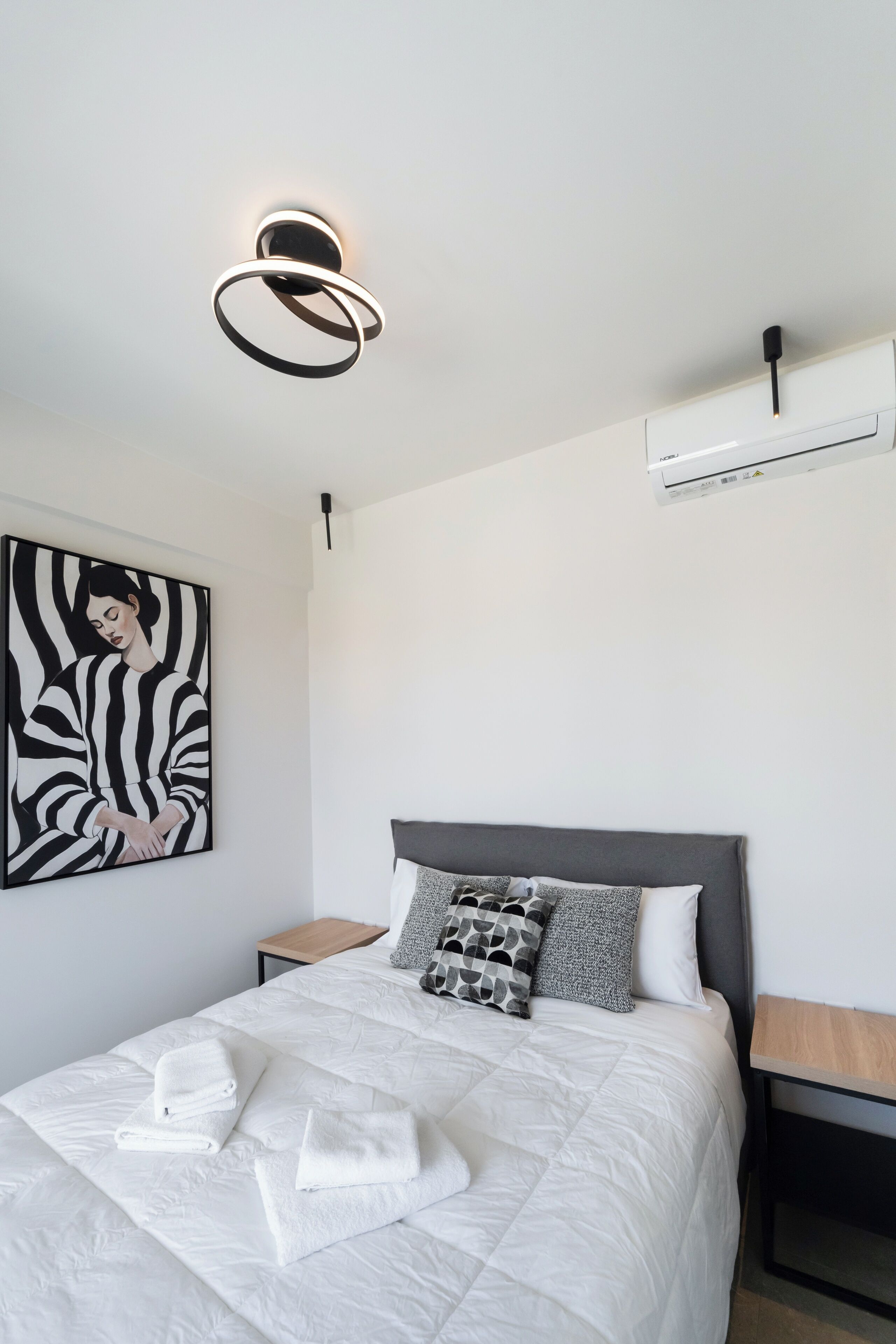 Une chambre moderne avec un grand lit, un climatiseur fixé au mur et un luminaire suspendu au plafond.