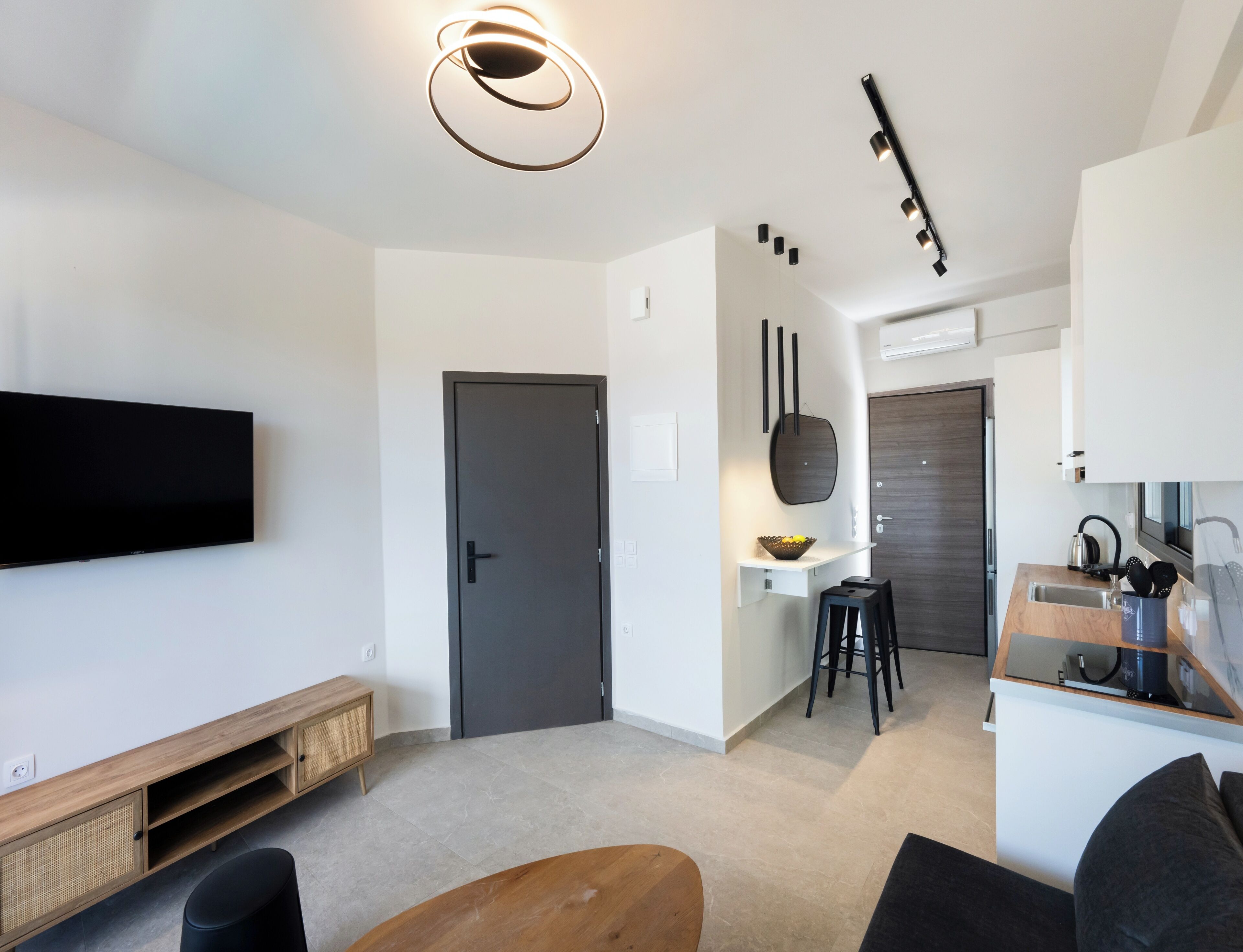 A modern living room with a flat-screen TV, a wooden coffee table, and a dark door.
