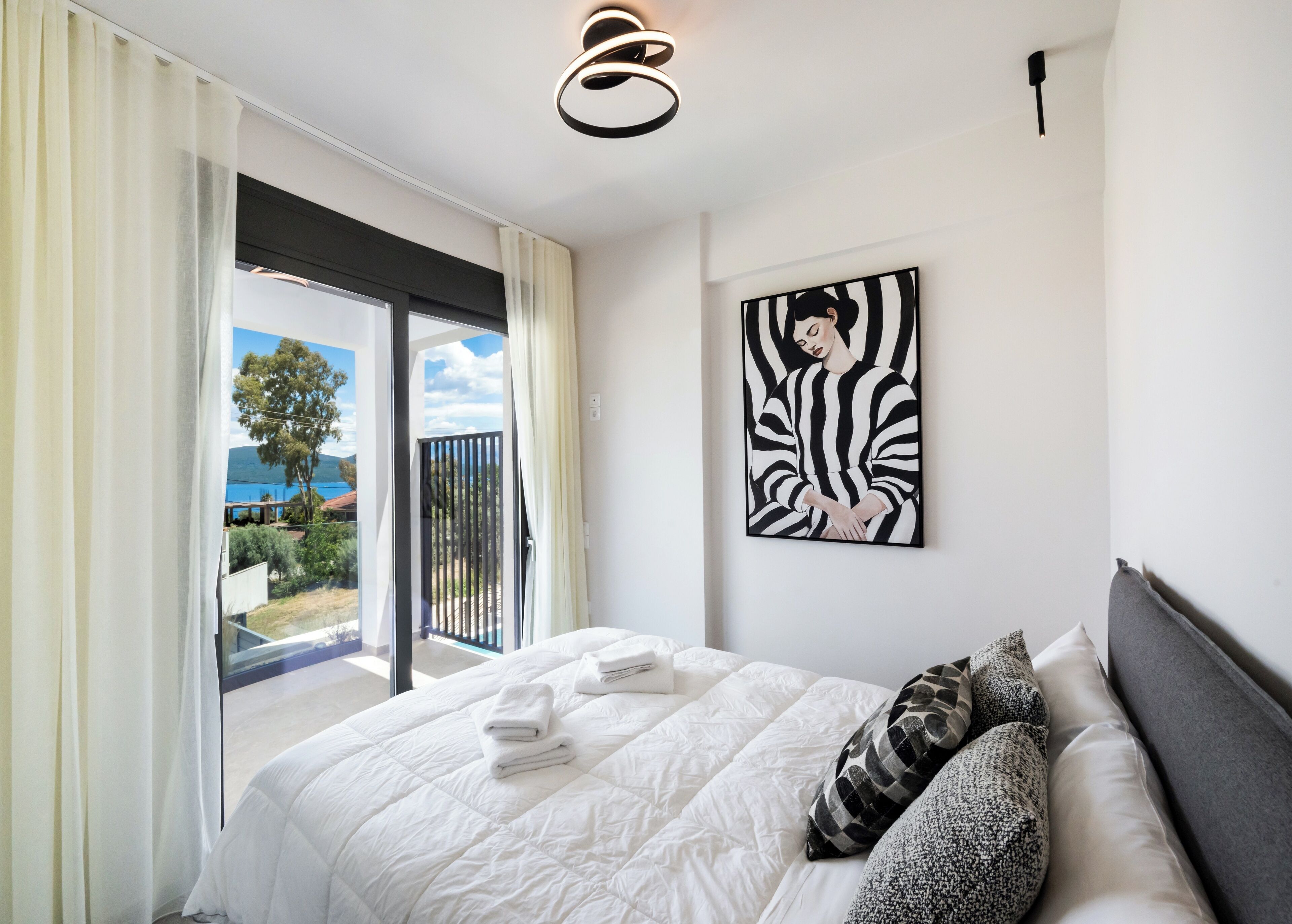 Een hotelkamer met een bed, een schilderij en uitzicht op het groen.