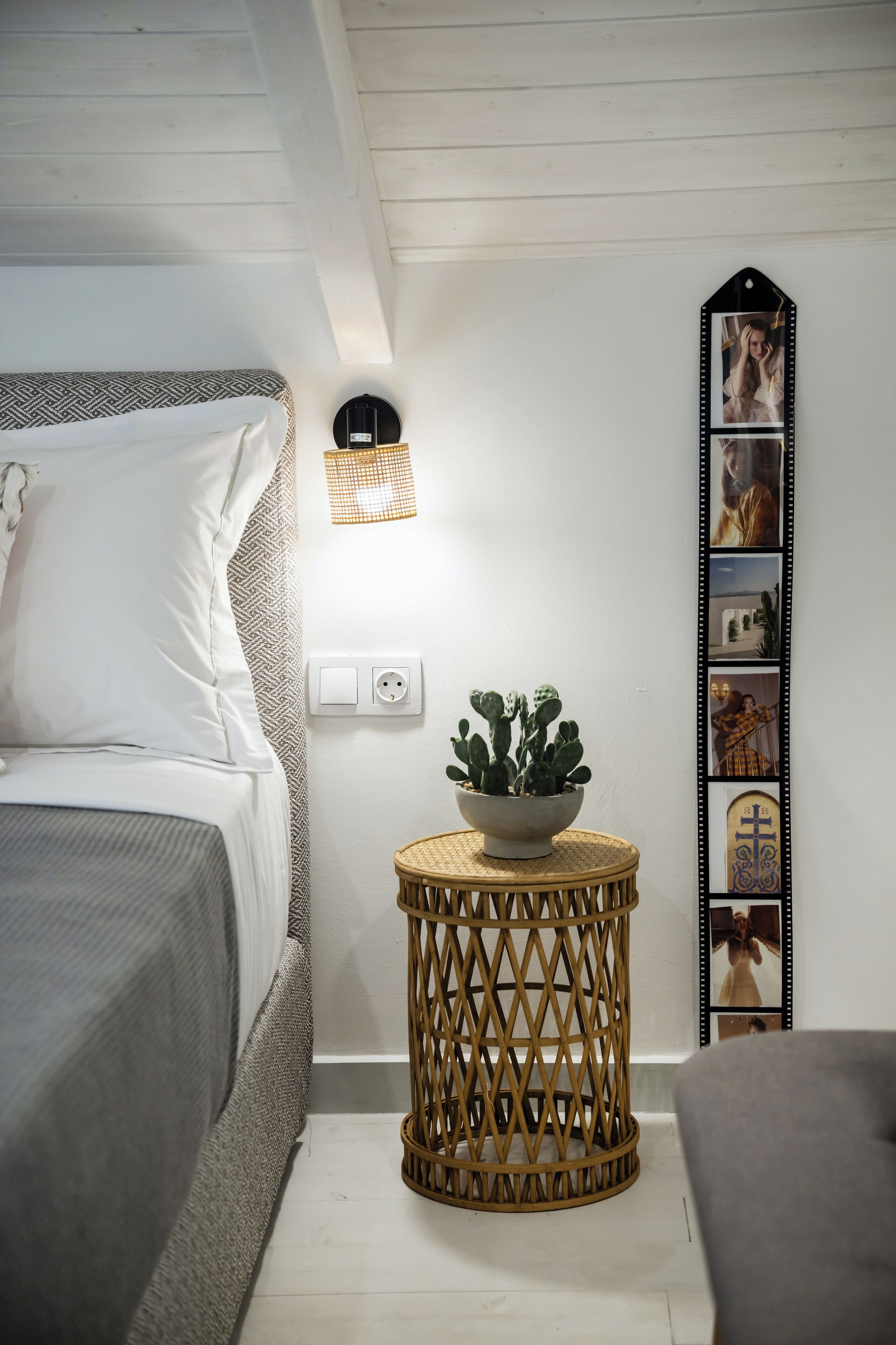 Ein Schlafzimmer mit einem Bett, einem Nachttisch mit Lampe, einer Wandsteckdose und einer dekorativen Wandverkleidung.