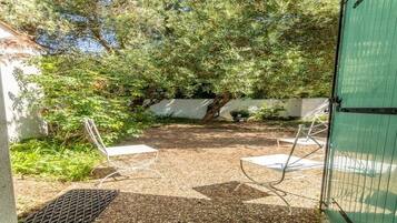 A patio area with a gravel surface, metal chairs, and a green fence.