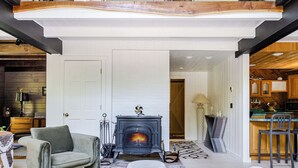 A living room with a fireplace, a sofa, and a dining area with a bar. - Pool & Hot Tub, Close to Hiking, Shops & Dining | Cragswood Lodge by AvantStay (Hudson Valley)