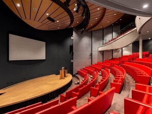 Experience the sleek, modern cinema hall with a curved seating arrangement and a large screen.