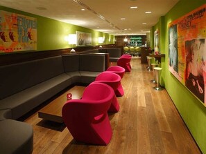 Relax in a stylish seating area with a sofa and chairs, surrounded by vibrant artwork and a bar.