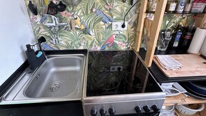 Une cuisine équipée d’un évier, d’une cuisinière et de divers ustensiles accrochés au mur.