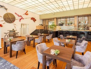 Relax in our spacious lobby with multiple seating areas and a bar, featuring a high ceiling and decorative elements.