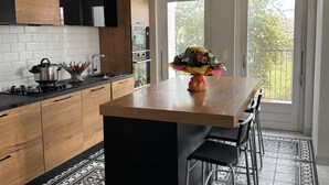 Een moderne keuken met een houten kookeiland, zwarte barkrukken en een patroon vloer.