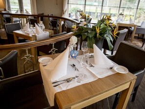 Enjoy a formal dining experience with a beautifully set table, elegant plants, and a view.