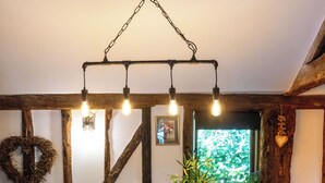 A kitchen with a wooden island, pendant lights, a window with a view, and a rustic wall design. - Historic Luxury 18th C Listed Barn Apartment (Maresfield)